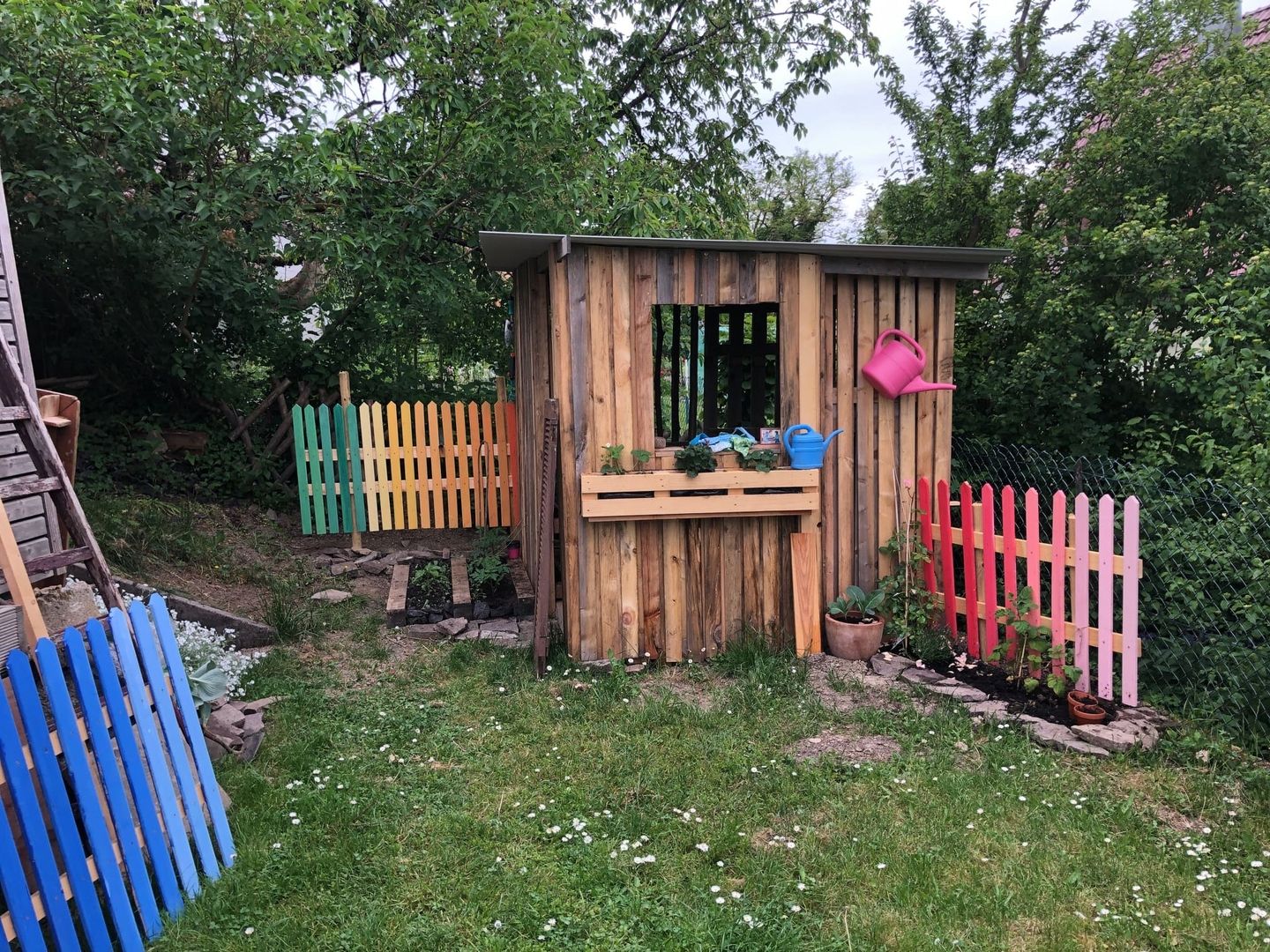 Eine Spielhütte aus Paletten steht im Garten